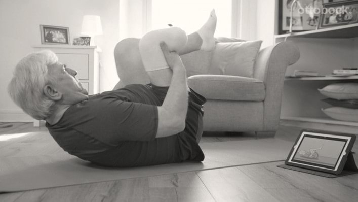 A man exercising while looking at a tablet