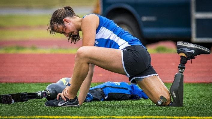 Christy stretching next to a running track