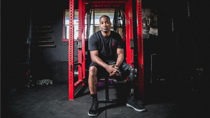 Brandon sitting on a weight bench in a gym with his X3 microprocessor knee