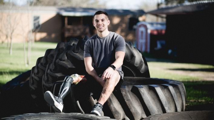 Marco sitting outdoors on oversized tractor tires with his X3 knee