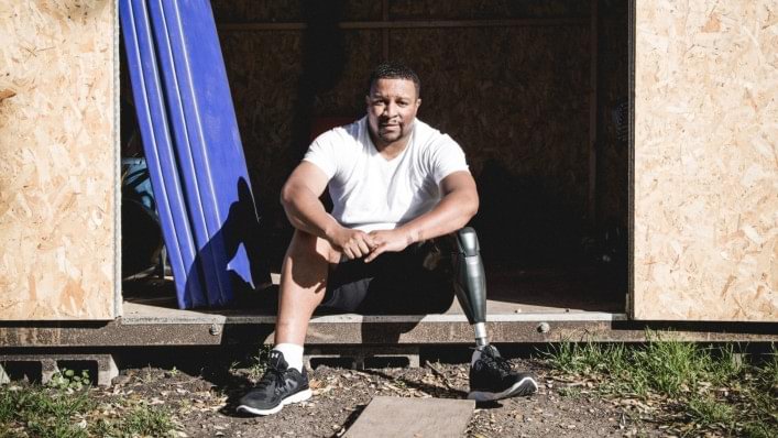 William sitting in a doorway of a workout gym wearing his X3 knee