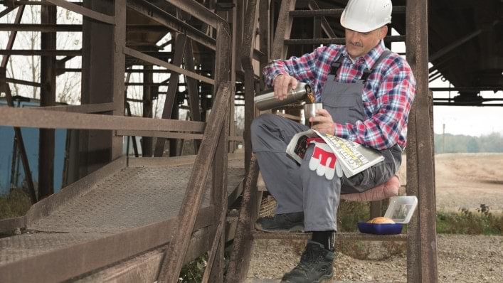 man sitting at work on a construction site with coffee while wearing agilium freestep