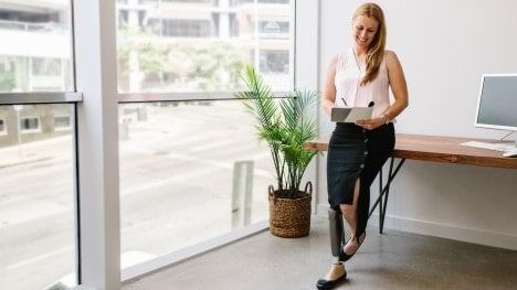 Katie standing at her desk with her C-Leg in an office
